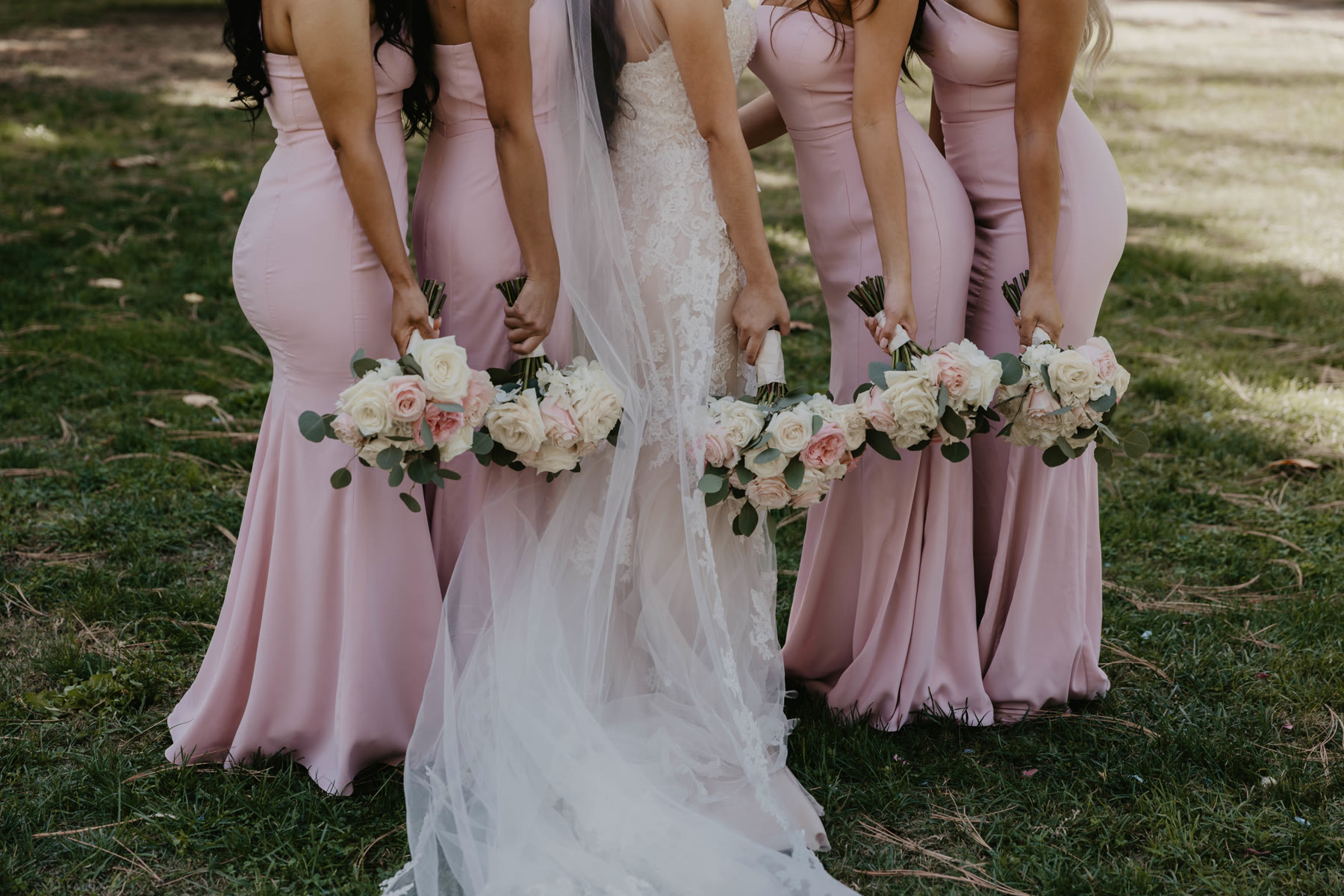 Bridesmaids in soft pink dresses holding bouquets beside the bride — Dejeu Crew wedding photography