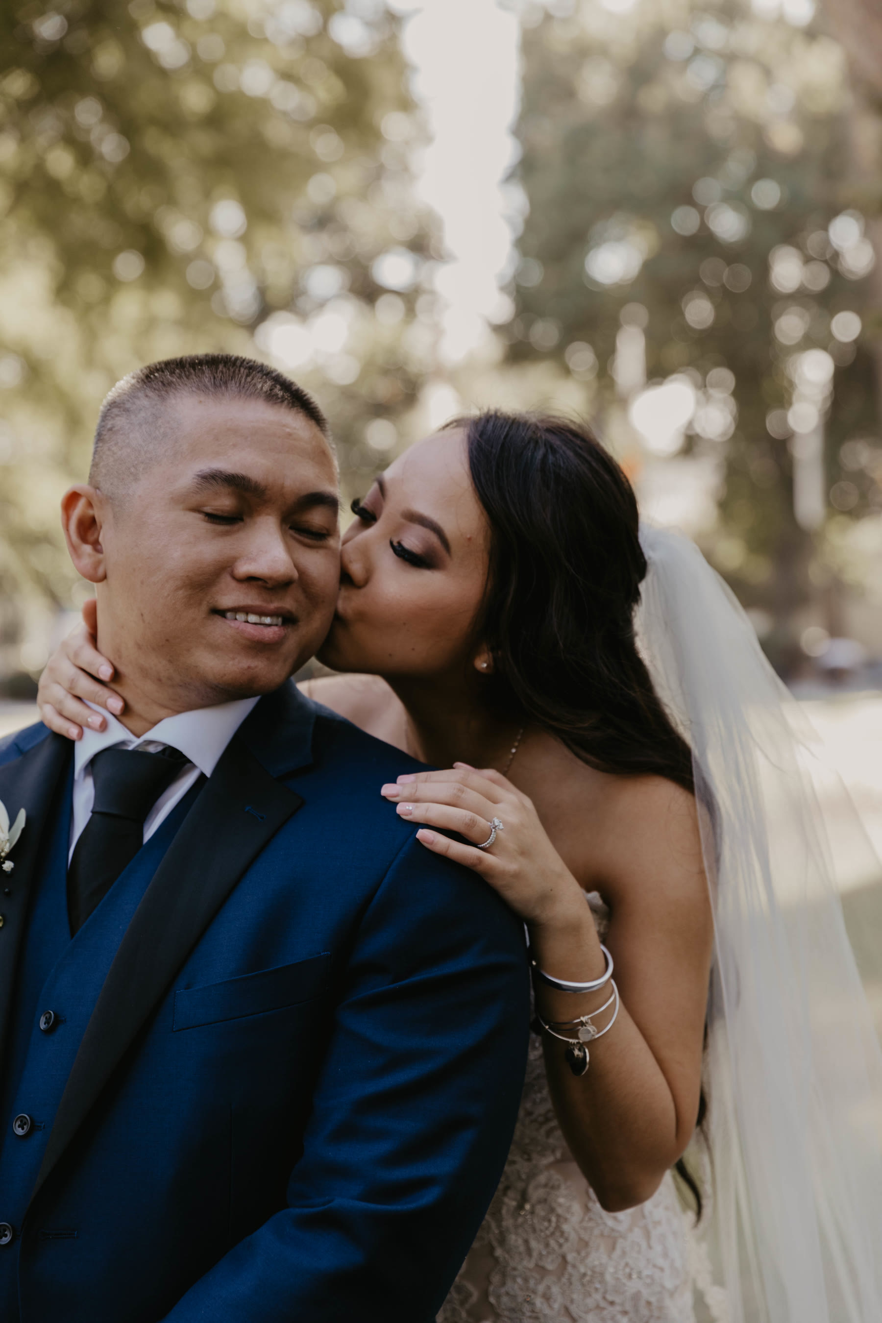 Groom kissing the bride on the cheek in warm golden-hour light — Dejeu Crew wedding photography