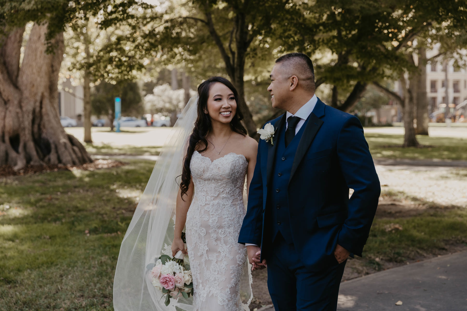 Newlyweds walking hand in hand down a path on their wedding day — Dejeu Crew wedding photography
