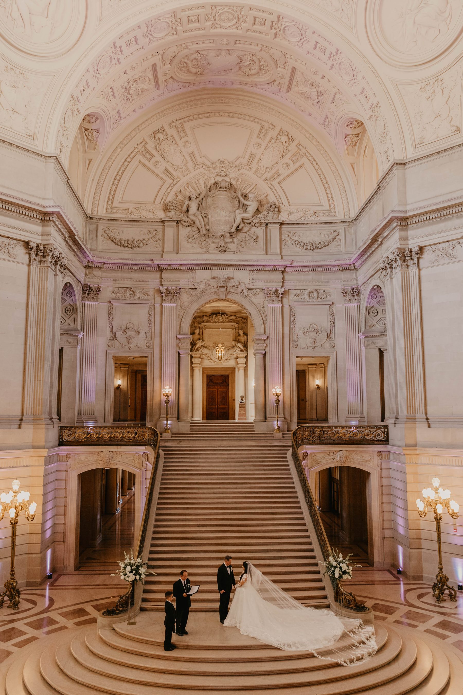 Bride and groom at the base of San Francisco City Hall’s symmetrical marble staircase — Dejeu Crew wedding photography