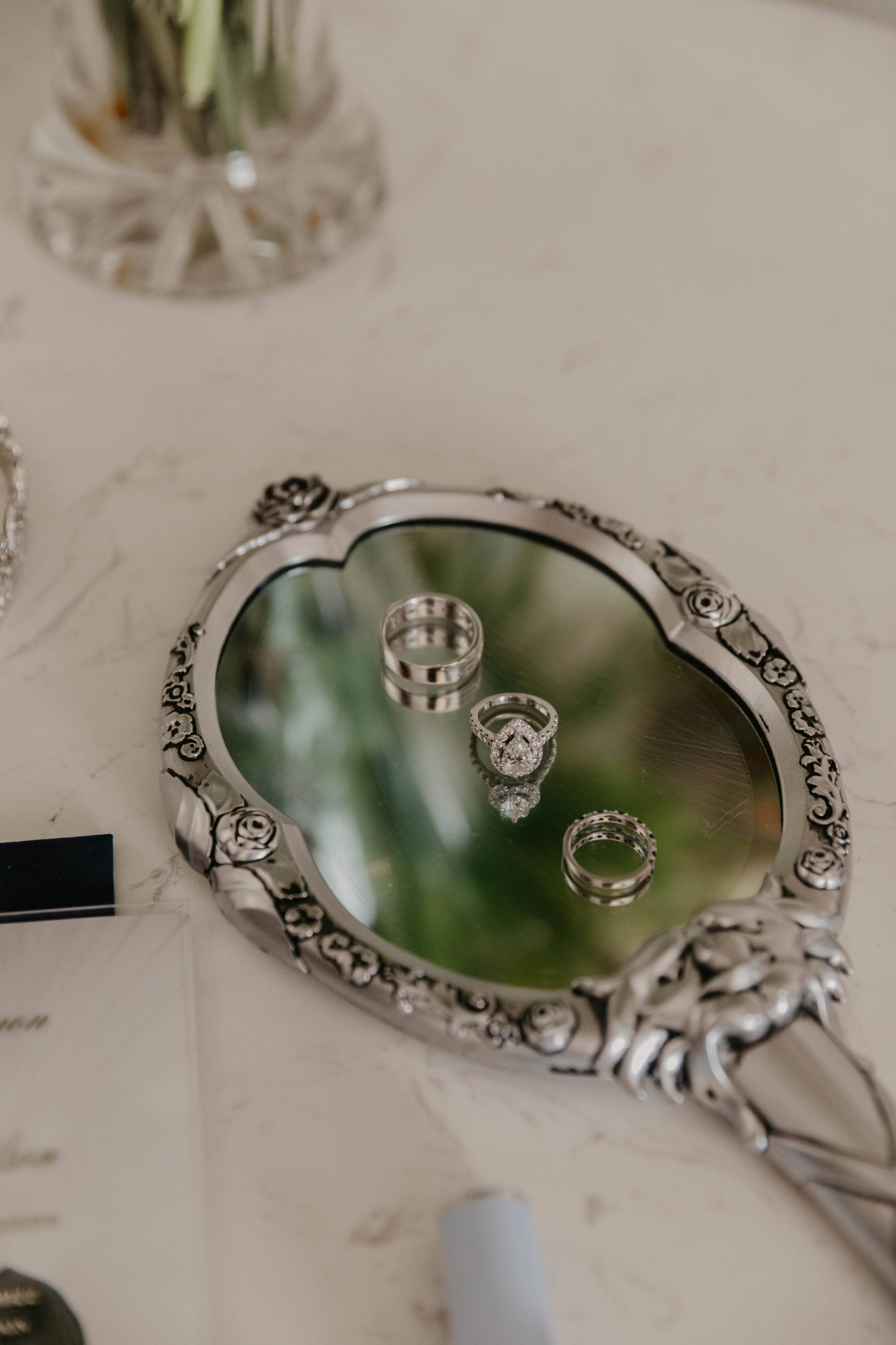 Wedding rings resting on an ornate vintage hand mirror — Dejeu Crew wedding photography