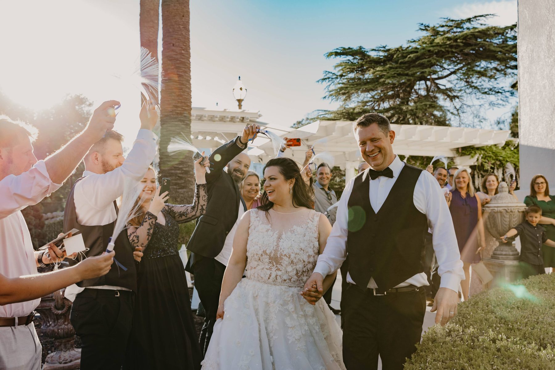 Newlyweds walking through cheering wedding guests outdoors — Dejeu Crew wedding photography