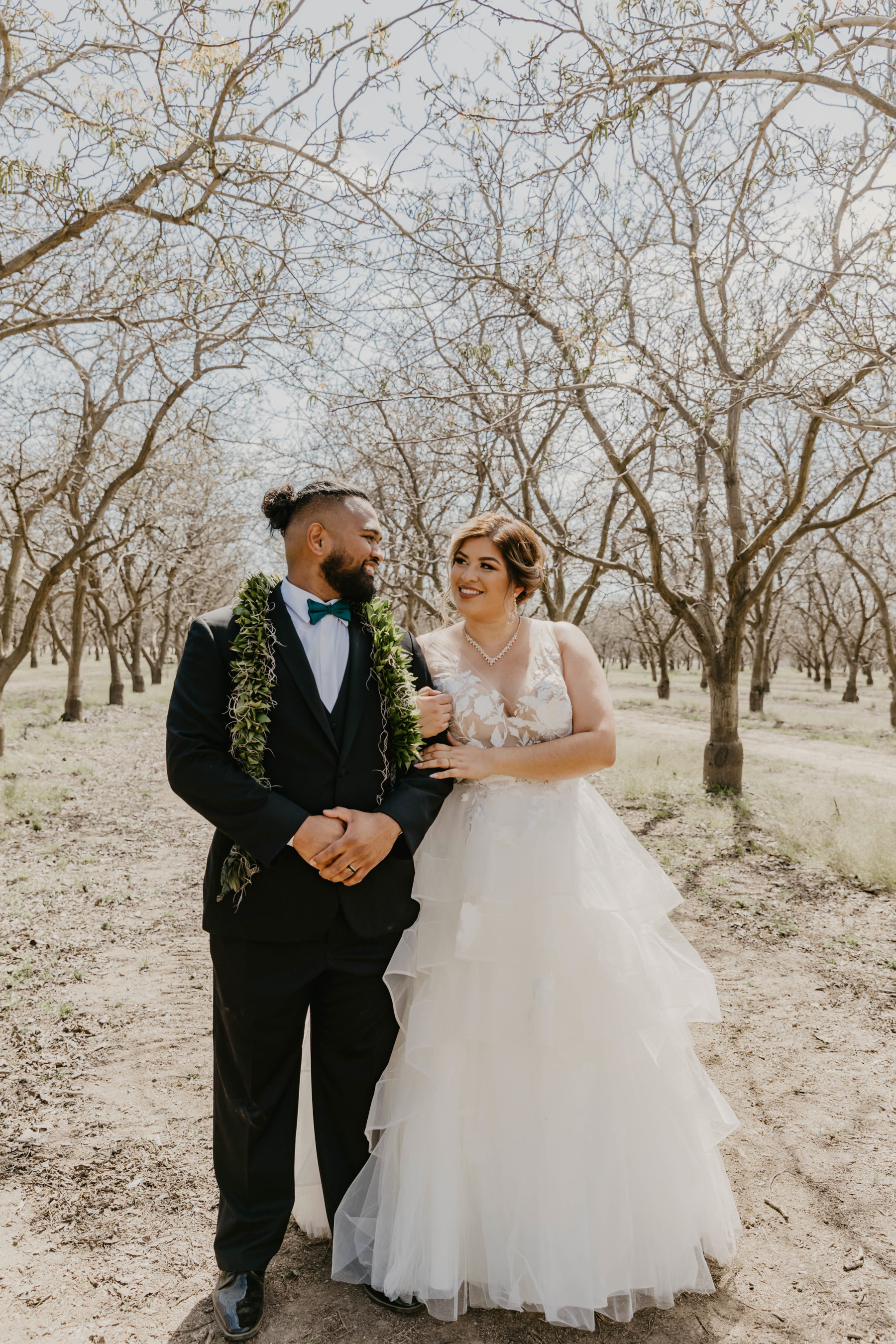 Bride and groom embracing in an orchard — portrait by Dejeu Crew, Modesto wedding photographer