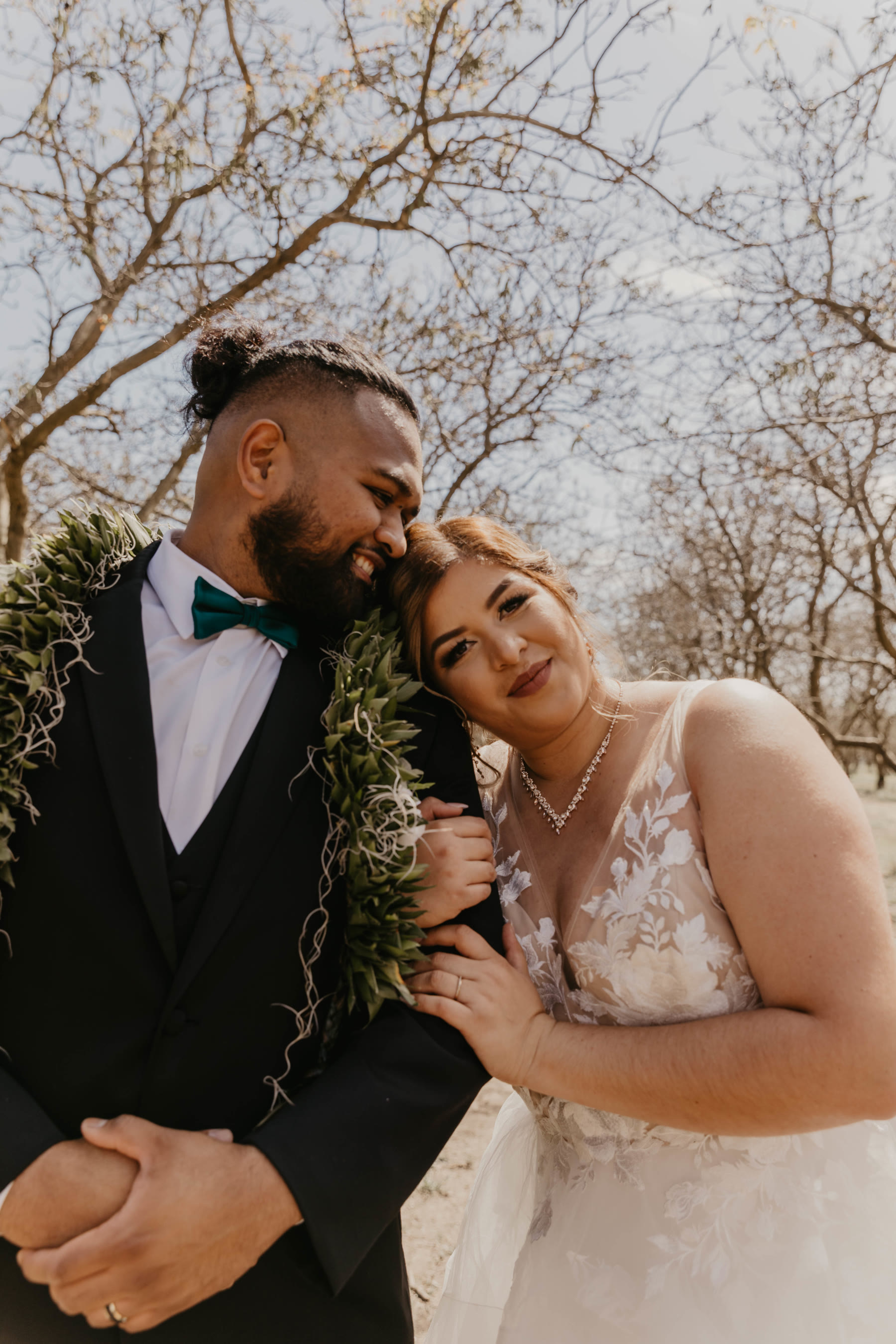 Low-angle portrait of a bride and groom framed by an orchard canopy and sky — Dejeu Crew wedding photography